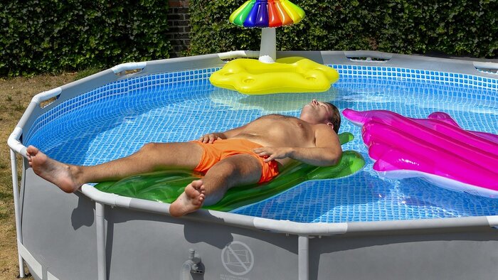 一名穿着泳裤的男子漂浮在地上的游泳池里放松。