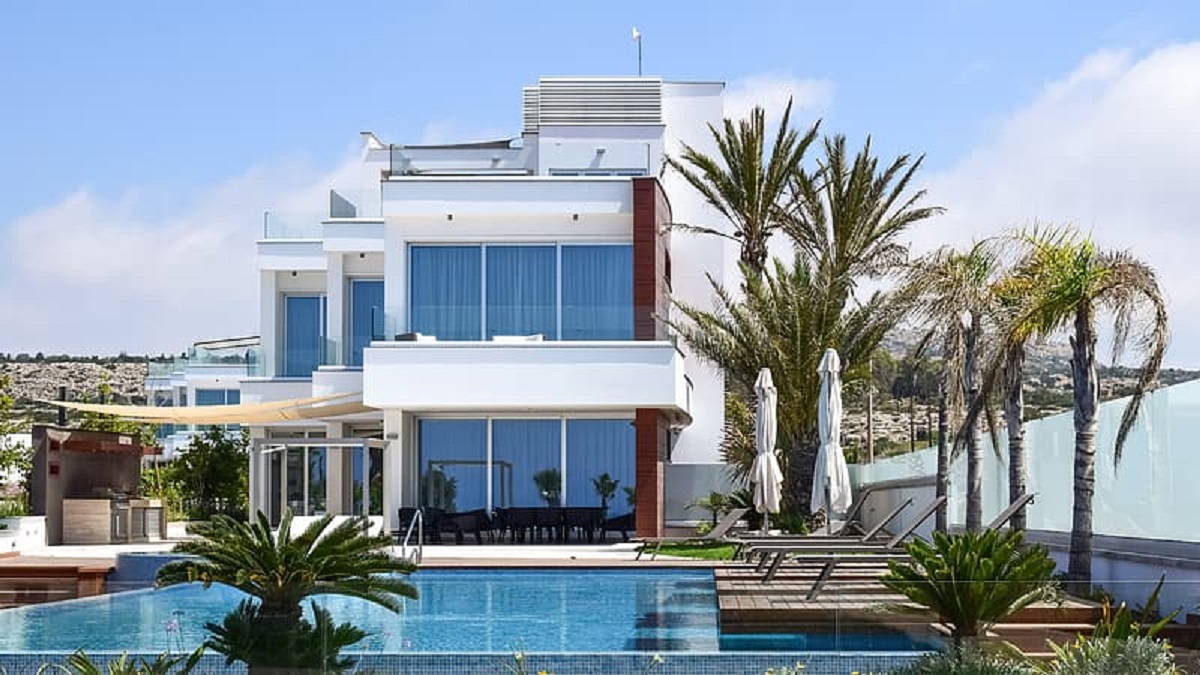 棕榈树环绕的白色房子前的游泳池