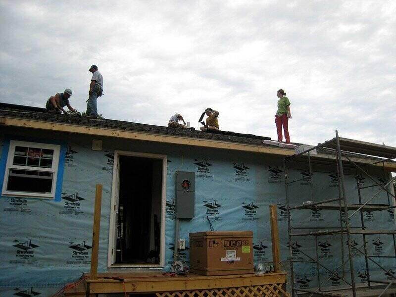 一群人在屋顶上，看起来正在铺沥青瓦