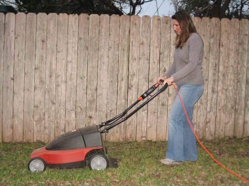 一名妇女正在使用电动割草机