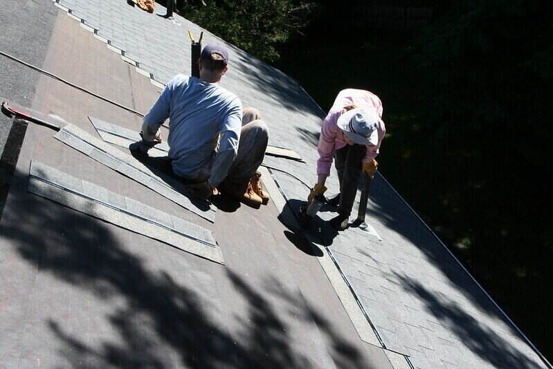 2名工人正在屋顶上更换瓦片