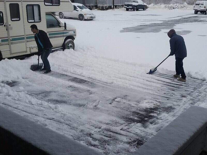 两个人在用雪铲铲车道