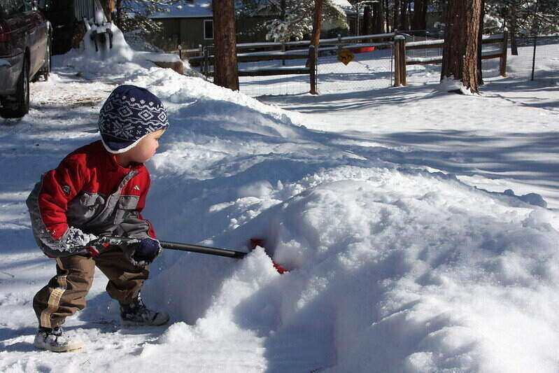小孩子用雪铲铲雪
