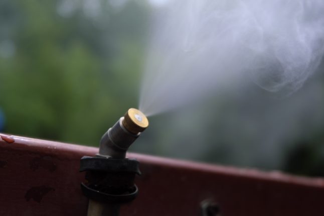 喷雾器或雾化器在绿树背景的花园里产生雾。